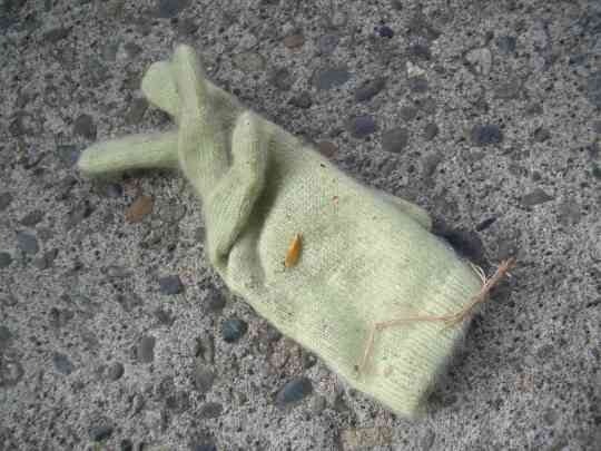 fuzzy light green woman's glove on a sidewalk