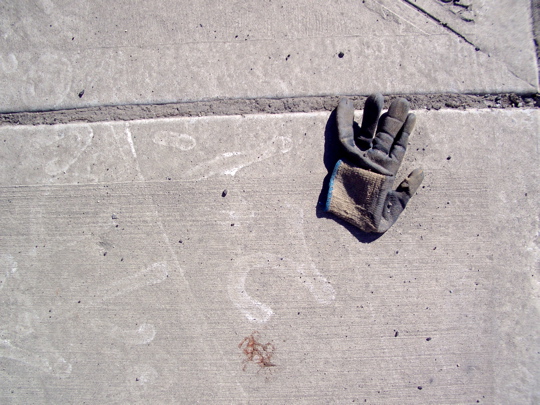 well-worn glove on dirty, spray-painted sidewalk