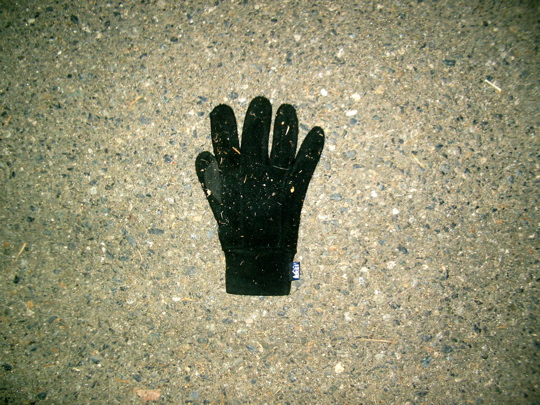black REI glove on pavement