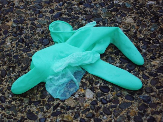 bluegreen rubber glove on pebbly sidewalk