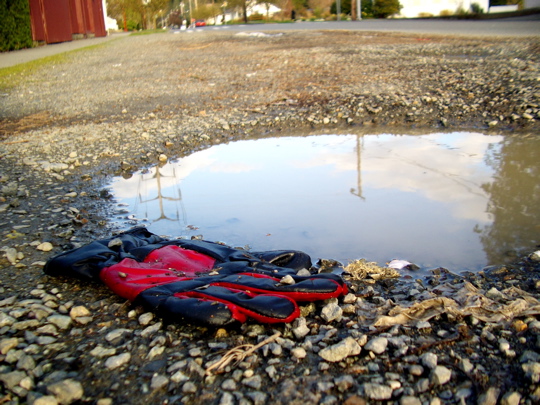 red and black glove near a puddle with reflection of sky and power lines